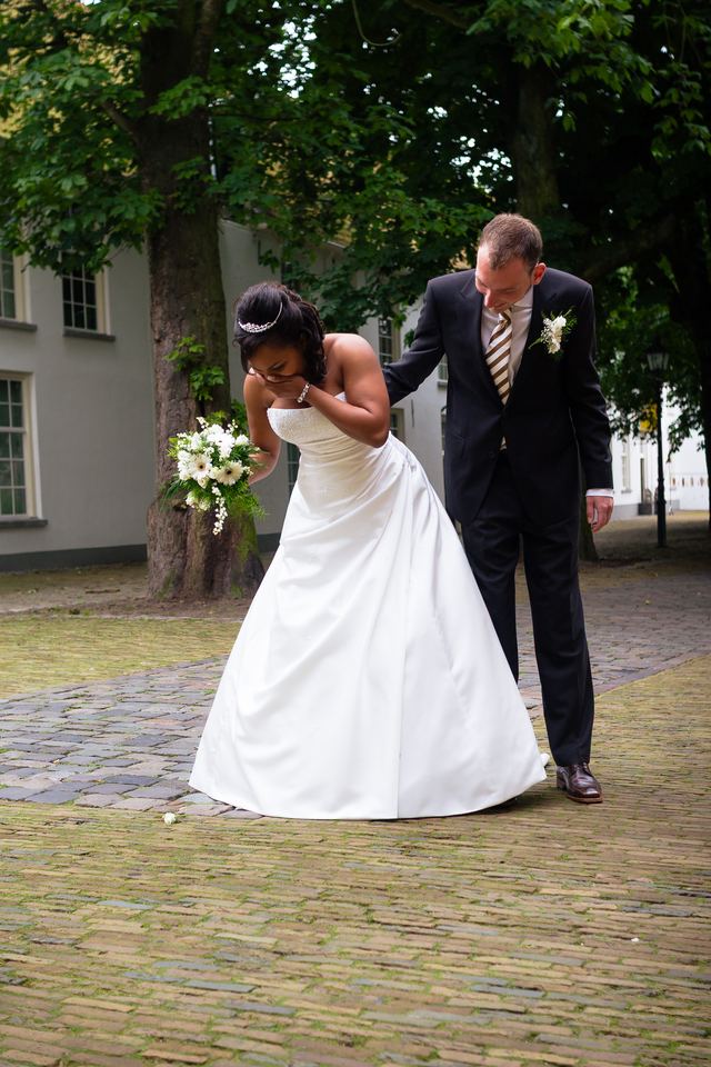 Bruidegom helpt bruid opstaan, ceremonieel moment bruiloft trouwfoto