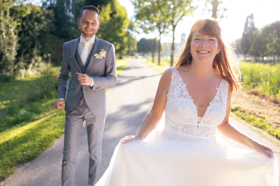 Bruidspaar loopt lachend op landweg, bruiloft together trouwfoto