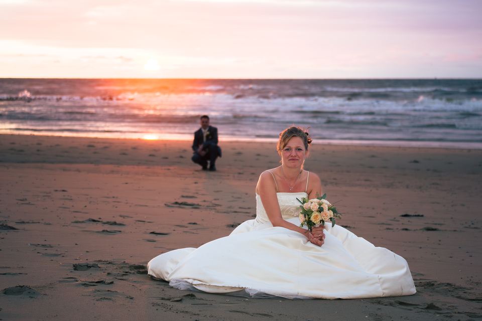 Bruid in witte trouwjurk op strand bij prachtige zonsondergang