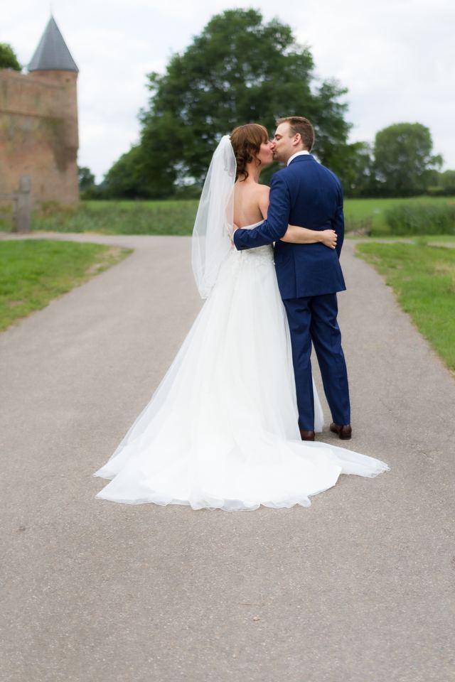 Bruidspaar kussend vor kasteel met witte sluier