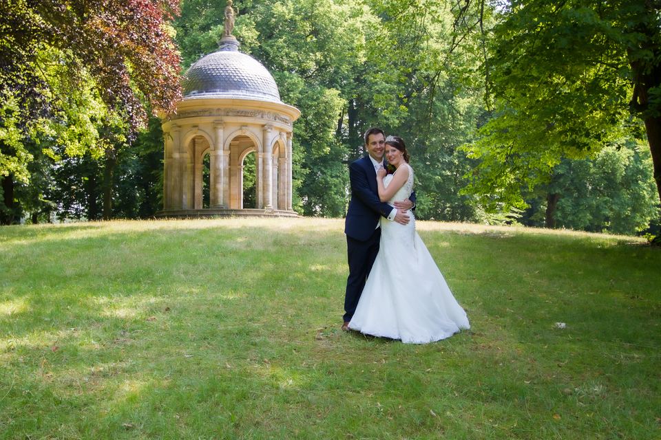 Bruidspaar omhelzing in park met gouden koepel monument op achtergrond