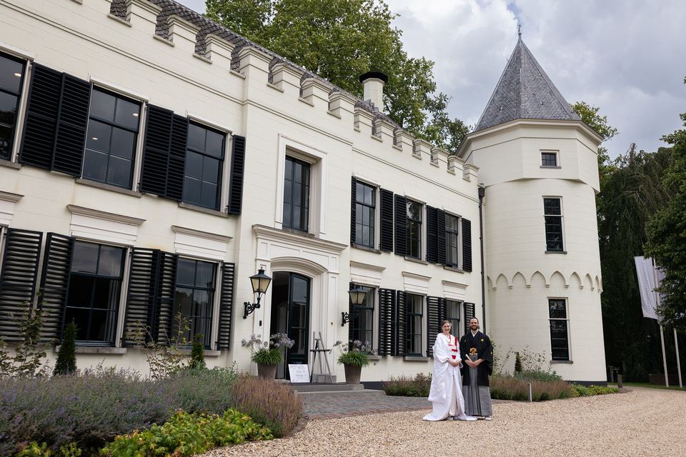 Bruidspaar staat voor wit landhuis met tuin, ceremonie afbeelding