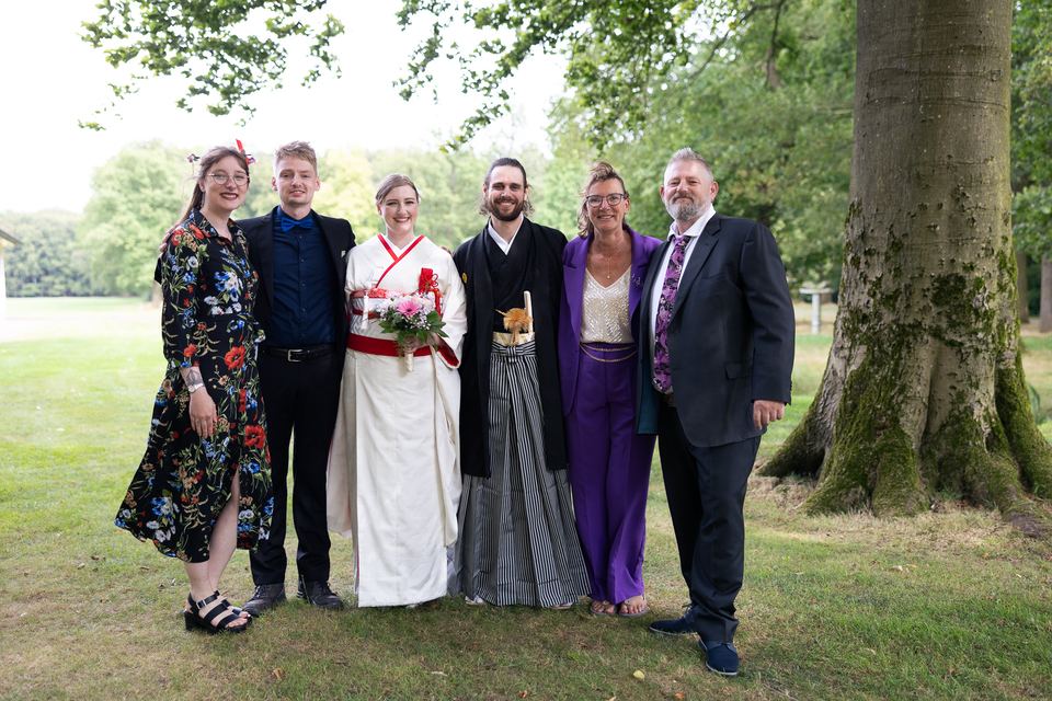 Bruidsfamilie groepsfoto in groen landschap bij grote boom
